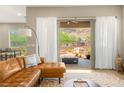 Living room with a view of a patio with mountain views, a leather sofa, and an area rug at 10890 Red Yucca Dr, Las Vegas, NV 89138