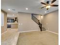 Open-concept living space with plush carpeting, staircase access, and a view into the modern kitchen at 11063 Mount George St, Las Vegas, NV 89179