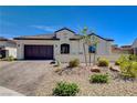 Well-manicured front yard with desert landscaping, featuring a stucco home with brick driveway and dark brown garage at 129 Major Bowling Pl, Henderson, NV 89011