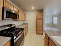 A modern kitchen featuring stainless steel appliances, granite countertops, and wooden cabinets at 2132 Tierra Del Verde St, Las Vegas, NV 89156