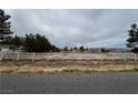Large lot with mature trees, a white fence, a home, and views of the local mountains at 2451 E Falcon St, Pahrump, NV 89048