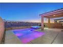 Backyard view of pool and hot tub with colored lights and covered patio with views to the desert landscape at 2787 Donatello Manor Pl, Henderson, NV 89044