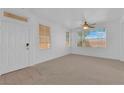 Bright living room featuring neutral carpet, large windows providing ample natural light, and ceiling fan at 5653 Mount Athos St, North Las Vegas, NV 89031