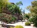 Beautifully landscaped exterior view of a building with mature trees and colorful flowering bushes at 5751 E Hacienda Ave # 137, Las Vegas, NV 89122