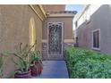 Home's entry door features a decorative security gate and desert landscaping at 72 Broken Putter Way, Las Vegas, NV 89148