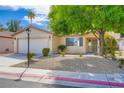 Traditional single-story home featuring a two-car garage, desert landscaping, and mature trees at 7547 Rolling River Dr, Las Vegas, NV 89131