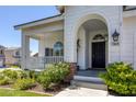 Inviting front porch with a porch swing, an arched entrance, and manicured landscaping at 7849 Meandering Light Ave, Las Vegas, NV 89131