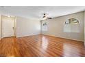 Spacious living room showcasing hardwood floors, a ceiling fan, and ample natural light from arched windows at 9325 W Desert Inn Rd # 104, Las Vegas, NV 89117