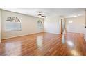 Bright living room featuring hardwood floors, a ceiling fan, and natural light streaming through arched windows at 9325 W Desert Inn Rd # 104, Las Vegas, NV 89117