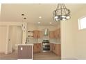 Open kitchen with stainless steel appliances, light wood cabinets, and island at 1025 Appaloosa Hills Ave, North Las Vegas, NV 89081
