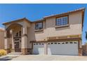 Two-story home featuring stucco siding, desert landscaping, an arched entryway, and a three-car garage at 1054 Broomfield Dr, Henderson, NV 89074