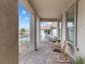 Inviting covered front porch with comfortable seating and decorative stone columns at 10863 Gardenova Ave, Las Vegas, NV 89166