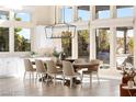 Sunlit dining area featuring a farmhouse table, designer chandelier, and large windows at 11015 Sanctuary Cove Ct, Las Vegas, NV 89135