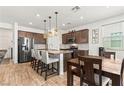 Bright kitchen features stainless appliances, eat-in island, wood-look tile flooring, and dining table at 438 Shimmering Sands Ave, North Las Vegas, NV 89031