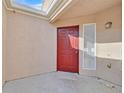 Enclosed porch with a red front door, stucco wall, and natural light, creating a welcoming entry at 4708 Cohiba Way, North Las Vegas, NV 89031