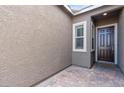 Covered front porch with paver flooring, a dark front door, and a side window providing ample natural light at 6421 Winecup St, Las Vegas, NV 89149