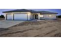 Charming single-story home featuring a three-car garage, arched entryway, and desert landscaping at 1131 Lupin St, Pahrump, NV 89048