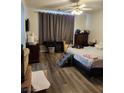 Bedroom featuring wood-look flooring, curtains, ceiling fan, and television on the wall at 1617 Stonefield St, Las Vegas, NV 89144
