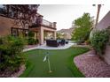 Beautiful backyard with putting green, covered patio, seating area, and mountain views at 2837 Turtle Head Peak Dr, Las Vegas, NV 89135