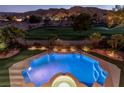 Aerial shot of the backyard pool area features a jacuzzi, night lighting, and golf course and mountain views at 2837 Turtle Head Peak Dr, Las Vegas, NV 89135