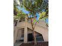 Exterior shot of a two-story condo building with a private entrance and mature tree at 3055 Key Largo Dr # 204, Las Vegas, NV 89120
