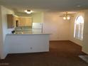 Open living area with brown carpet, ceiling fan, and breakfast bar leading into the kitchen at 4050 Pacific Harbors Dr # 214, Las Vegas, NV 89121