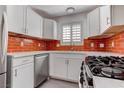 Modern kitchen featuring stainless steel appliances, white cabinetry, stylish countertops, and a vibrant tile backsplash at 5811 Pack Trl, Las Vegas, NV 89118