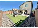 Backyard features artificial turf, play structure, lounge area, and rock landscaping at 7468 Wellfleet Bay Ave, Las Vegas, NV 89179