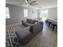 Open-concept living space with tile flooring, a ceiling fan, and gray L-shaped sofa at 7990 Formitch Ct, Las Vegas, NV 89166