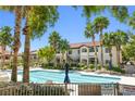Enjoy this spacious community pool with palm trees, lounge chairs and tables, and nearby parking for easy access at 3451 Desert Cliff St # 103, Las Vegas, NV 89129