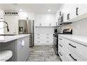 Modern kitchen with stainless steel appliances, white cabinetry, and a gray island with barstool seating at 551 Swiss Cottage Ave, Las Vegas, NV 89178