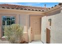 Inviting entryway featuring a beige front door, textured walls, and a decorative outdoor light fixture at 612 Moontide Ct, Henderson, NV 89011