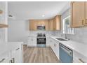 Bright kitchen boasts stainless appliances, tile backsplash, wooden cabinets and plank flooring at 747 Greenbriar Townhouse Way, Las Vegas, NV 89121