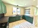 Bright kitchen with unique green cabinets, dark countertops, stainless steel appliances, and wood grain flooring at 7537 Brisa Del Mar Ave, Las Vegas, NV 89179