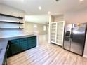 Kitchen with floating shelves, stainless steel refrigerator, unique green cabinets, and an open view to the living room at 7537 Brisa Del Mar Ave, Las Vegas, NV 89179