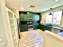 This kitchen features green cabinets, stainless steel appliances, and ample counter space for cooking at 7537 Brisa Del Mar Ave, Las Vegas, NV 89179