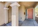 View of the front porch and entryway with columns and a peach-colored front door at 9022 Sosa Creek Ave, Las Vegas, NV 89149
