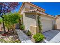 Inviting front entrance with a paved walkway, lush greenery, a well-manicured lawn, and a two-car garage, enhancing curb appeal at 10645 Lace Vine Arbor Ave, Las Vegas, NV 89144