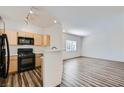 Kitchen showcasing black appliances, light wood cabinets, and wood-look floors open to living area at 1881 W Alexander Rd # 1092, North Las Vegas, NV 89032
