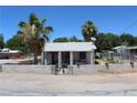 Front exterior view shows the home, palm trees, and a small wall enclosing the front yard at 192 W Alma Ave, Overton, NV 89040