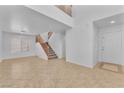 Bright living room with neutral colors, tile flooring, and staircase leading to the second floor at 7621 Breed Hill St, Las Vegas, NV 89149