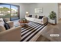 Staged living room with white furniture, striped rug, and view of balcony with mountain views in this modern condo at 950 Seven Hills Dr # 217, Henderson, NV 89052