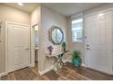 Entryway with wood floors, elegant table, decorative mirror, and a view of the downstairs powder room at 9785 W Meranto Ave, Las Vegas, NV 89178