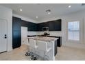 Modern kitchen features sleek dark cabinets, granite counters, stainless appliances, and a central island with seating at 9844 Kings Glen St, Las Vegas, NV 89141