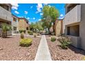 Well-maintained exterior of condominium buildings with mature trees, shrubs, and a stone pathway at 3151 Soaring Gulls Dr # 1066, Las Vegas, NV 89128