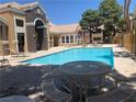 Community pool with tables, chairs, and lounge chairs surrounded by community buildings at 8101 W Flamingo Rd # 1102, Las Vegas, NV 89147