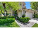 Inviting entrance with mature landscaping, a wrought iron fence, and a view of the attached two-car garage at 916 Pro Players Dr, Las Vegas, NV 89134