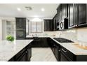Well-lit kitchen showcasing granite countertops, dark cabinets, stainless steel appliances, and wood-style tile flooring at 12426 Mosticone Way, Las Vegas, NV 89141