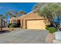 Beige home featuring desert rock landscaping, an attached two-car garage, and a driveway at 1904 Hot Oak Ridge St, Las Vegas, NV 89134
