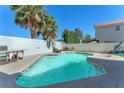 Sparkling pool with a concrete surround and privacy wall provides a refreshing escape at 5612 Royal Castle Ln, Las Vegas, NV 89130